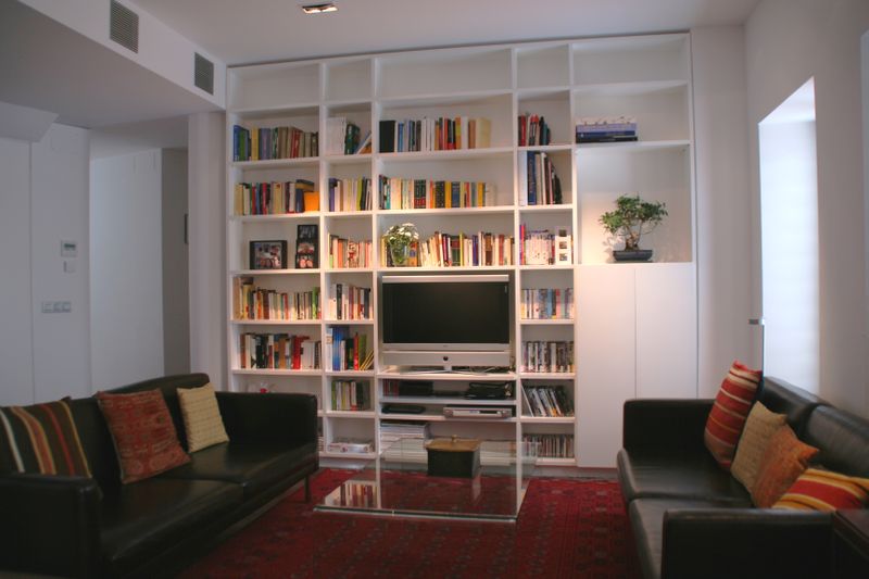 Librería realizada en dm lacado blanco. Se ha integrado el televisor y una zona cerrada para guardar vajilla y otros objetos.