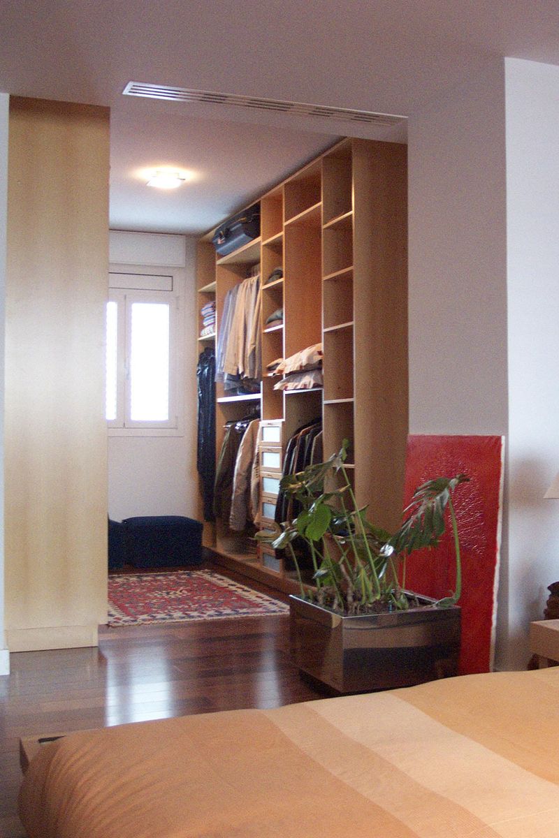 Vestidor sin puertas integrado en el dormitorio principal acabado en madera de haya en su color natural.